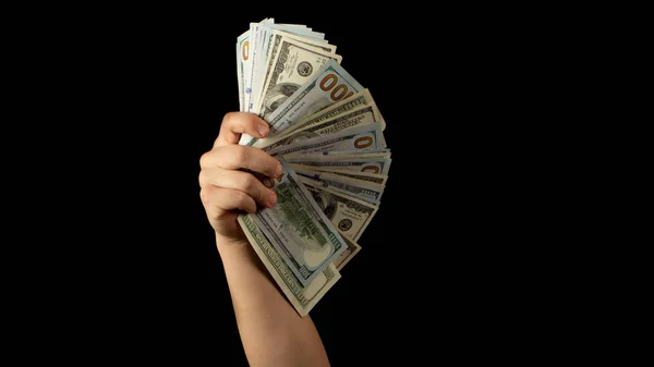 Fan of dollars in a male hand on a black background close up