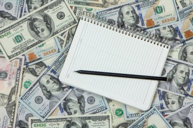 Yüz dolarlık banknotların arkaplanındaki beyaz defter. Kapat.