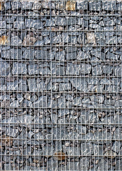 Gabion, a stone wall with a metal grid of gray granite texture — Stok fotoğraf
