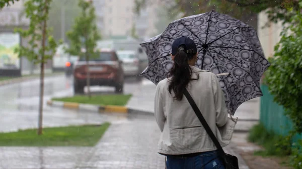 La gente si nasconde dalla pioggia sotto gli ombrelloni in una giornata piovosa sulla strada della città concetto di cattivo tempo — Foto Stock