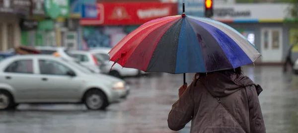 La gente si nasconde dalla pioggia sotto gli ombrelloni in una giornata piovosa sulla strada della città concetto di cattivo tempo — Foto Stock