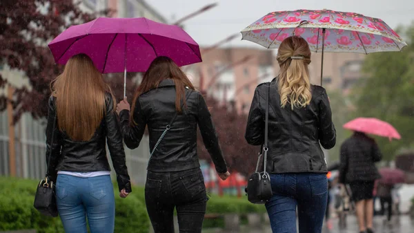 La gente si nasconde dalla pioggia sotto gli ombrelloni in una giornata piovosa sulla strada della città concetto di cattivo tempo — Foto Stock