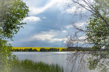 Küçük bir göl üzerinde yağmur, bir tarım arazisi kraliyet alanı ile