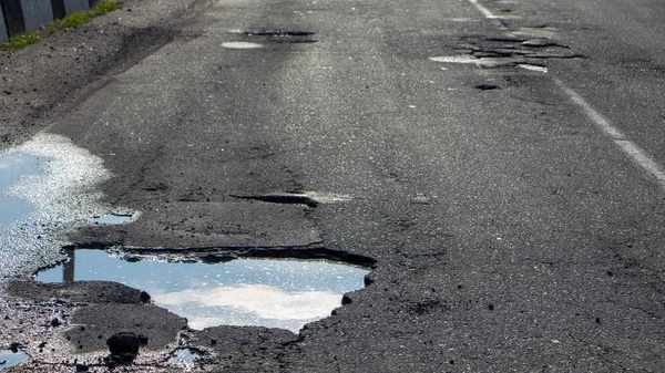 There are many potholes on the roadway close up — Stock Photo, Image