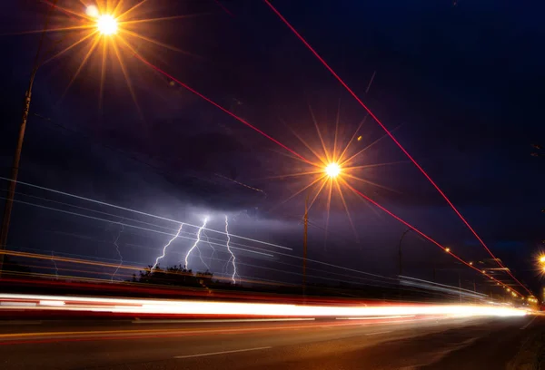 Las descargas de rayos en el cielo nocturno sobre la carretera —  Fotos de Stock