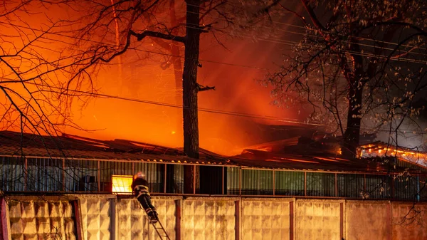 Fire in factory building at night. Firefighters try to put out the fire