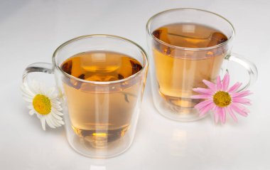 beyaz bir masada papatya çiçekleri ile bitkisel çay fincan