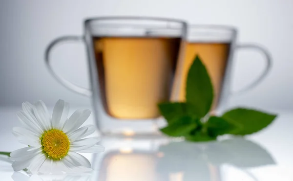 Šálek bylinkového čaje s heřmánkovým květenkem na bílém stole — Stock fotografie