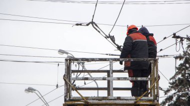 Kuledeki işçiler, tramvay otobüsleri için iletişim şebekesini onarıyor