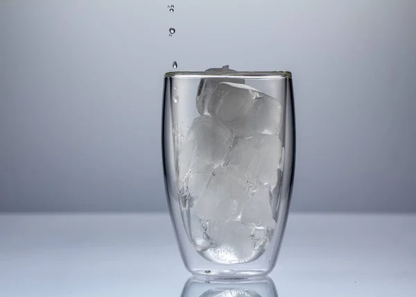 Verser de l'eau dans du verre sur fond bleu fermer — Photo