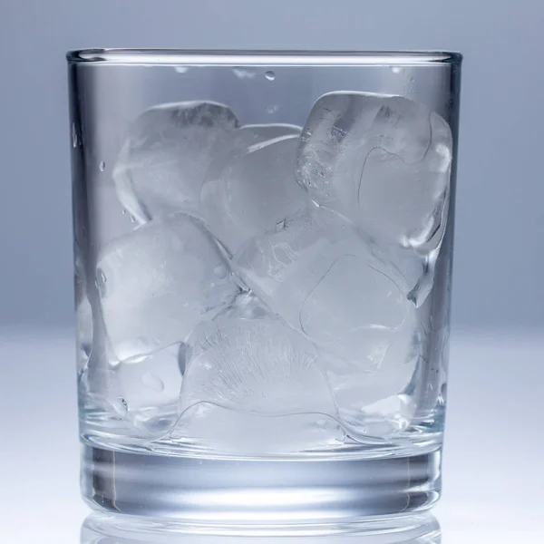 Hälla vatten i glas på blå bakgrund närbild — Stockfoto
