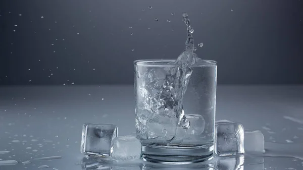Gießen von Wasser in Glas auf blauem Hintergrund Nahaufnahme — Stockfoto