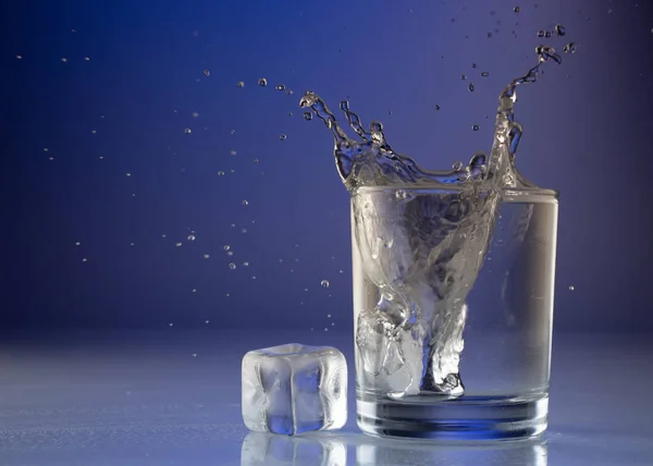 Gießen von Wasser in Glas auf blauem Hintergrund Nahaufnahme — Stockfoto