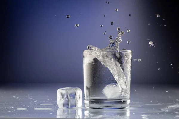 Verter agua en un vaso sobre fondo azul de cerca —  Fotos de Stock