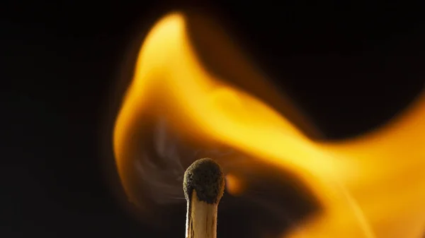 Brennendes hölzernes Streichholz mit rotem Streichholzkopf auf schwarzem Hintergrund. — Stockfoto