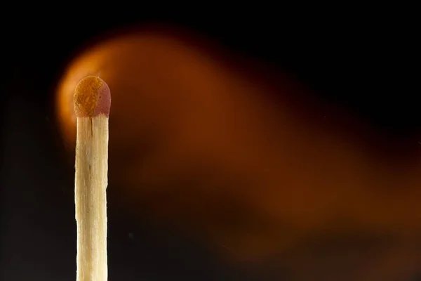 Brennendes hölzernes Streichholz mit rotem Streichholzkopf auf schwarzem Hintergrund. — Stockfoto