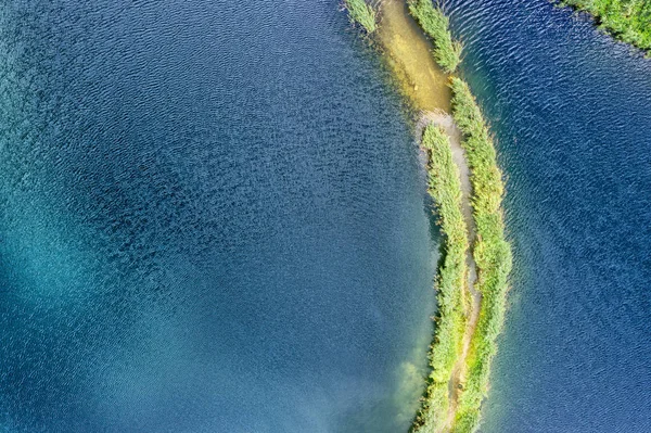 Mały pluć ze ścieżką pokrytą zieloną trawą po obu stronach, na jasnym jeziorze. Fotografia lotnicza — Zdjęcie stockowe