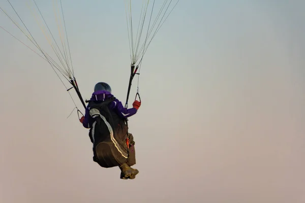 Gleitschirmflieger bereitet sich darauf vor, unter freiem Himmel gegen den Sonnenuntergang zu fliegen. Fallschirm im Rucksack im Freien — Stockfoto