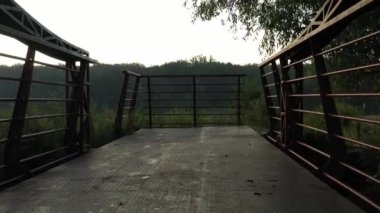 Ukrayna 'daki Irpin şehrinin seti üzerindeki küçük bir nehrin üzerindeki kırmızı metal köprü, düşük yavaş insansız hava aracı uçuşu.