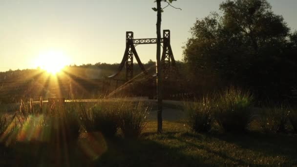 El puente de metal rojo sobre un pequeño río en el terraplén de la ciudad de Irpin en Ucrania, vuelo de aviones no tripulados lento bajo — Vídeos de Stock