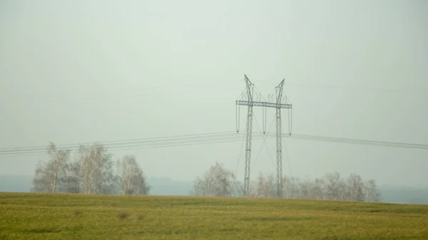 High voltage electricity transfer lines and pylon in a fog — Stock Photo, Image