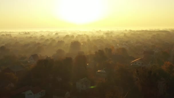 朝の霧に覆われた村の上の夜明けの4kビデオ。太陽の光が霧を美しくカット. — ストック動画