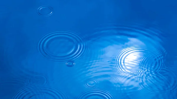 Concept, rainy weather. Circles on the water from raindrops. Blue natural background.