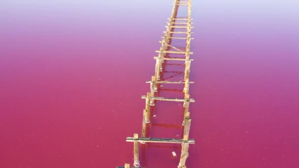 Pink lake and old wooden structures. Aerial view. — Stock Video