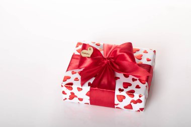 Kırmızı kalp dokusuyla beyaz kağıda sarılmış hediye kutusu. Ve pembe bir kurdeleye sarılmış.