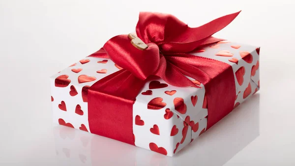 Gift box wrapped in white paper with red heart texture. And wrapped in a pink ribbon. — Stock Photo, Image