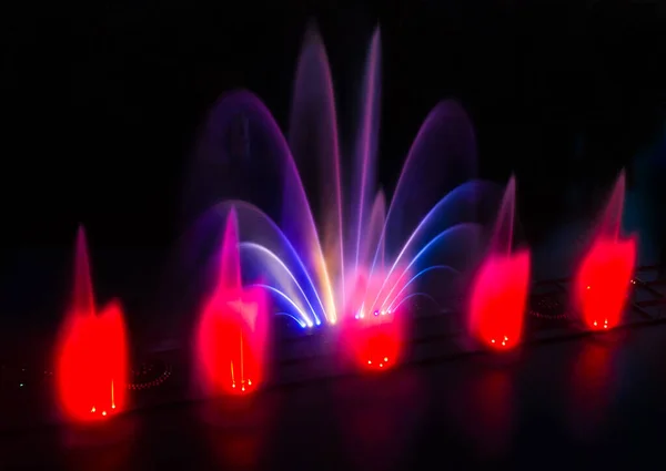 Drone view of a colored fountain on the river at night.
