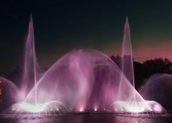 Drone view of a colored fountain on the river at night.