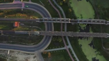 Tren metal bir demiryolu köprüsünden geçiyor.