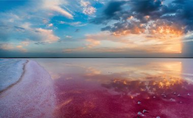 Lemuria Gölü 'nde gün batımı. Kırmızı tuz kıyıda uzanıyor. Bulutlar su yüzeyine yansıyor..