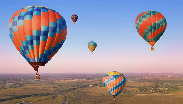 Düzlüklerde havada beş renkli balon var. Ovaların üzerinde havada balonlar.