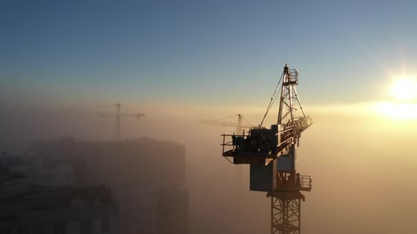 Żurawie budowlane o świcie we mgle porannej. — Wideo stockowe