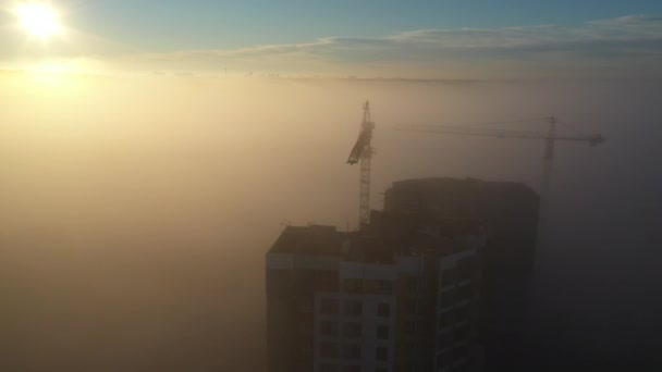 Żurawie budowlane o świcie we mgle porannej. — Wideo stockowe