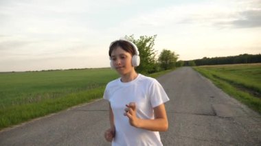 asfalt üzerinde çalışan ve müzik kulaklık, ağır çekim kız atlet trenler