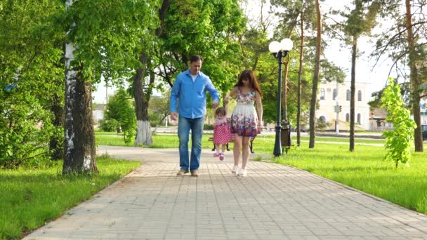 Mama en papa spelen met baby verhogen baby door handen omhoog, meisje springen en lachen, familie wandeling in het Park in de zomer — Stockvideo