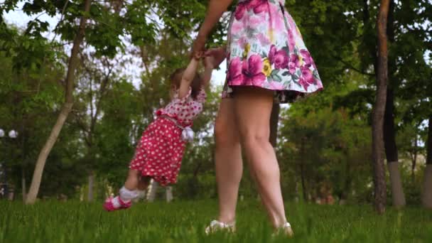 Mamma sta girando sorridente bambino tra le braccia in aria. Bambino piccolo sta giocando con il genitore nel parco verde — Video Stock