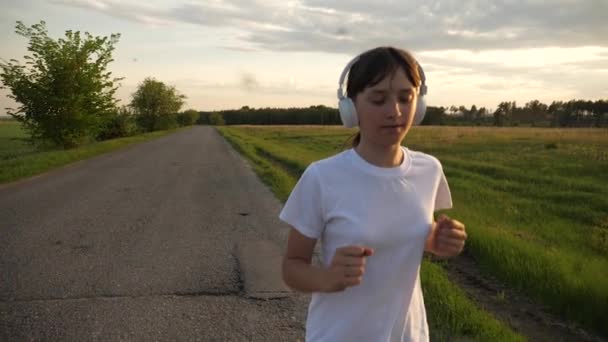 Estilo de vida esportivo, menina em fones de ouvido música executando no treinamento de estrada — Vídeo de Stock