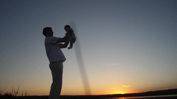 Vater spielt mit Baby bei goldenem Sonnenuntergang. — Stockvideo