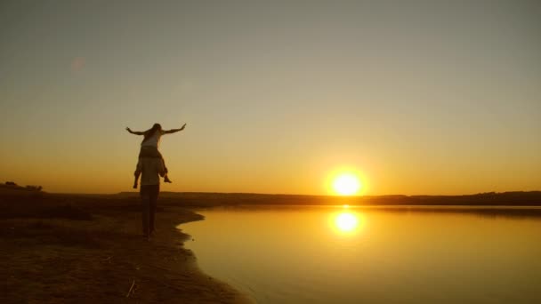 Fille et père heureux marchant le long de la plage au coucher du soleil , — Video