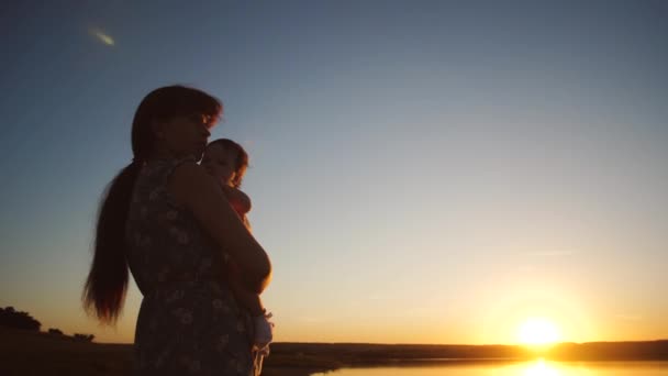 Mamá sostiene al bebé en brazos al atardecer . — Vídeos de Stock
