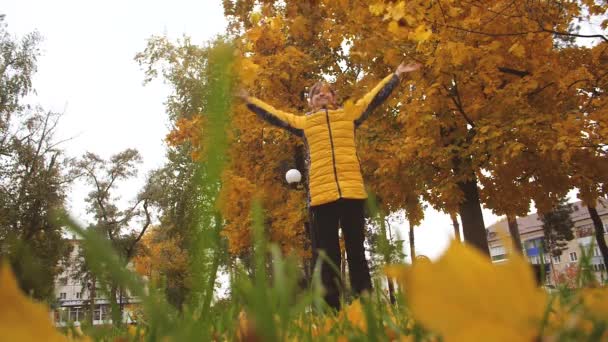 Tizenéves lány dobtak juhar levelek ősszel, mosolyogva. Lassú mozgás. — Stock videók