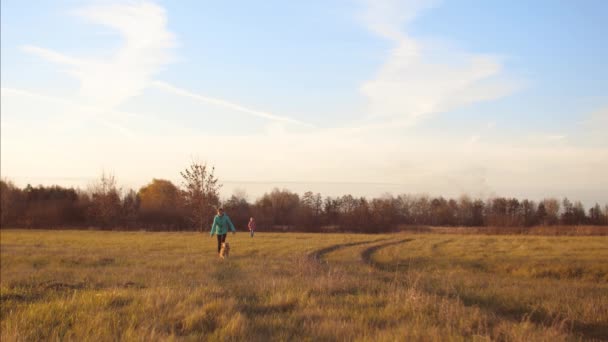 Les adolescentes courent avec un chien à travers le champ et rient . — Video