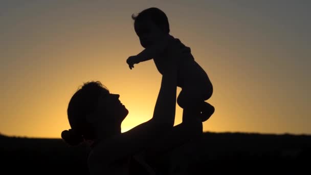 Mother throws baby above red sunset. Slow motion. — Stock Video