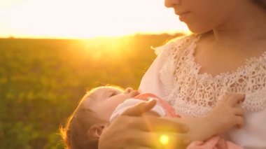gün batımı, ağır çekim çekim, annesinin kollarında küçük bir bebek uyur