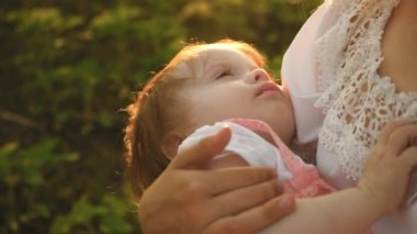 küçük bir çocuk annesi kollarında uykuya dalar, anne ve kızı yaz park, ağır çekim çekim yürüyor