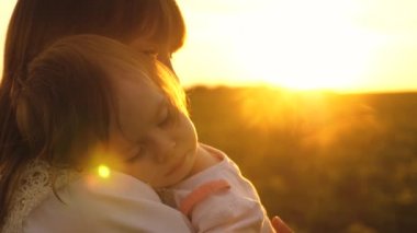 küçük çocuk annesi kollarında uykuya daldı, anne ve kızı günbatımında yaz, ağır çekim çekim parkta yürümek